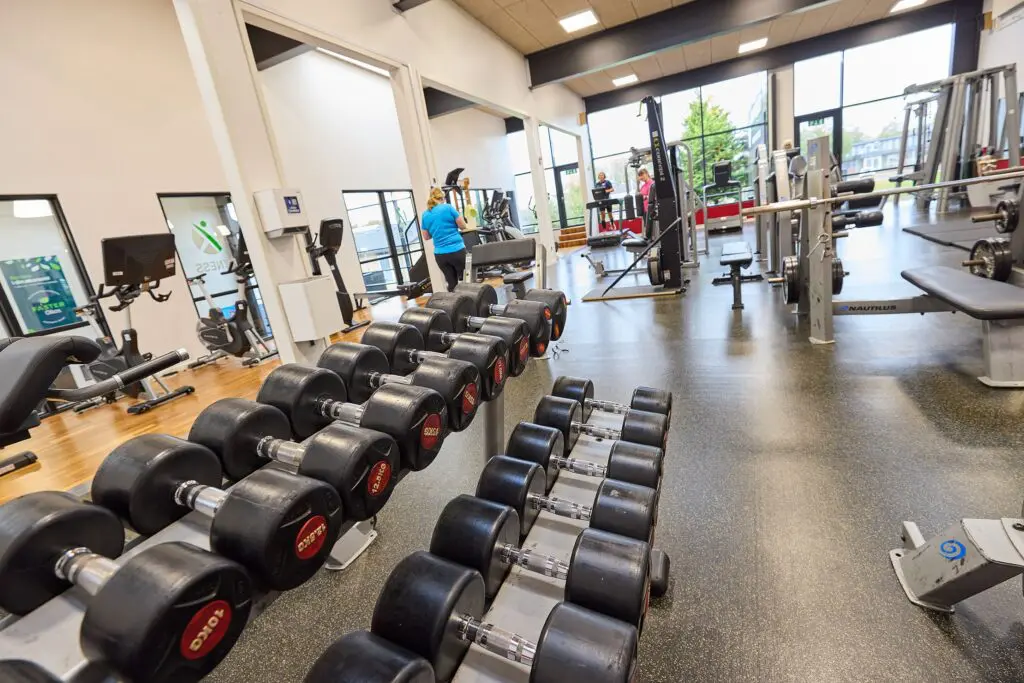 Rækker af håndvægte på stativ og styrketræningsmaskiner i fitnesscenteret hos Kraftværket Videbæk.