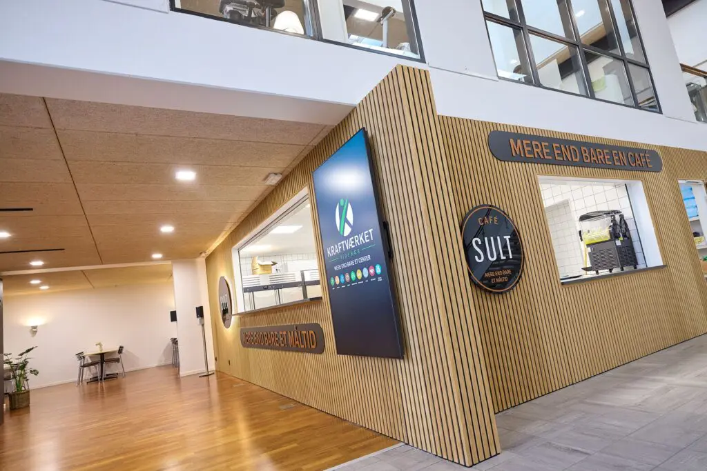 Café SULTs facade med trælameller og serveringsluger i forhallen hos Kraftværket Videbæk