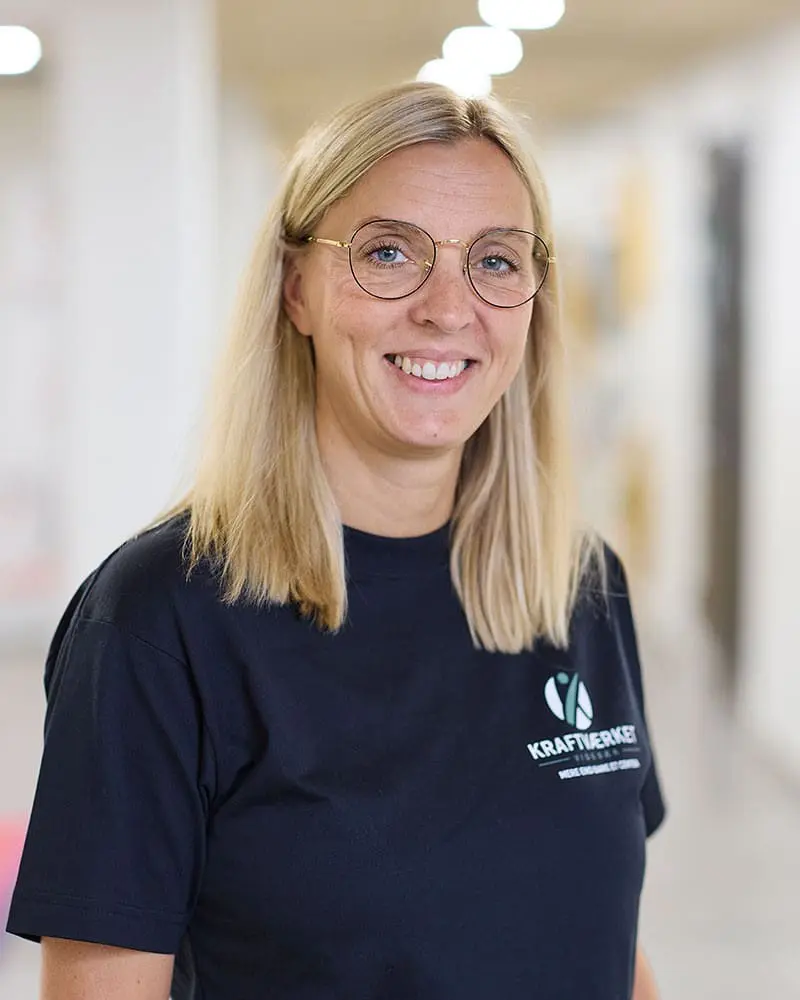 Portræt af smilende Dorte Søndergaard, kontorassistent hos Kraftværket Videbæk, iført t-shirt med logo