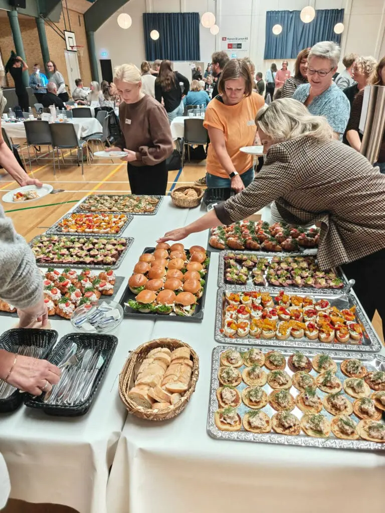 Gæster tager mad fra en stor buffet med sliders og tapas i idrætshallen i Kraftværket Videbæk