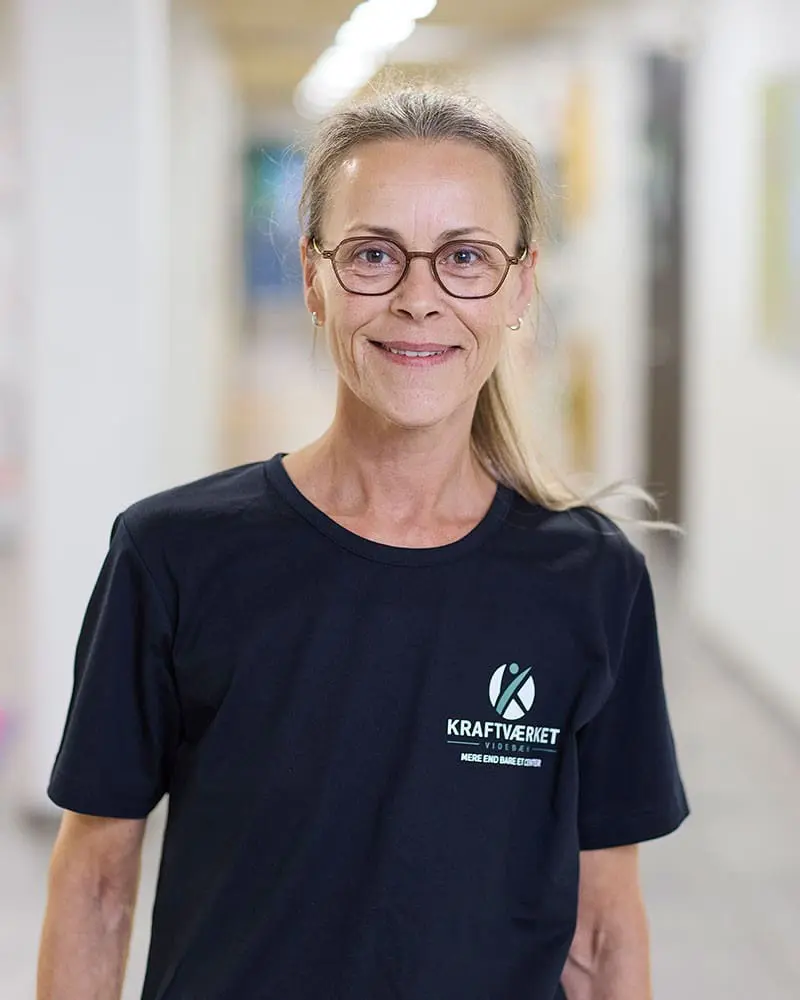Portræt af Inger Lisby, køkkenmedarbejder hos Kraftværket Videbæk, iført sort t-shirt med logo